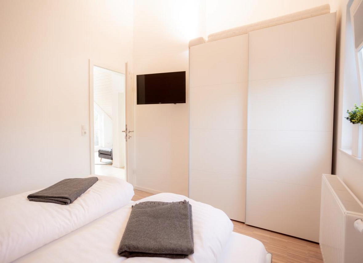 Modernes Schlafzimmer mit großem Kleiderschrank und TV